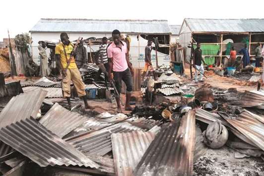 Armed members of a local defence group inspect the damages of a suicide blast in Maiduguri earlier this month.