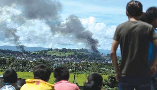 People watch as smoke billows from houses after aerial bombings by Philippine Air Force planes on militant positions in Marawi on the southern island of Mindanao yesterday.