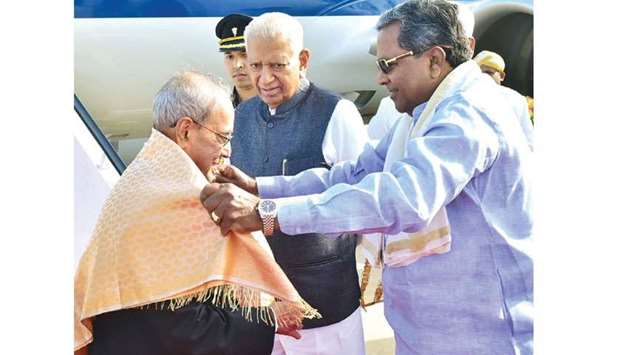 Karnataka Chief Minister Siddaramaiah drapes a shawl on President Pranab Mukherjee as Governor Vajubhai Rudabhai Vala looks at the HAL airport in Bengaluru yesterday.
