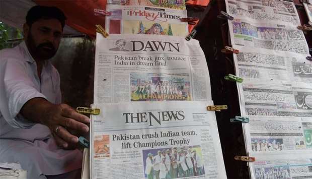 A Pakistani vendor arranges morning newspapers featuring front page coverage of Pakistan's victory a