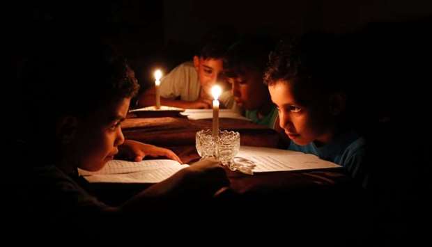 Palestinian children at home reading books by candle light due to electricity shortages in Gaza City. File picture, June 13, 2017