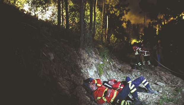 Exhausted firefighters rest metres away from a wildfire at Penela, Coimbra, central Portugal.