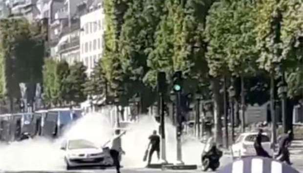 French police officers engage with a suspect outside a car at the Champs Elysees in Paris on Monday.