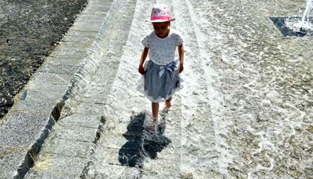 A girl refreshes herself at a fountain in Kiev during a hot day on Tuesday.