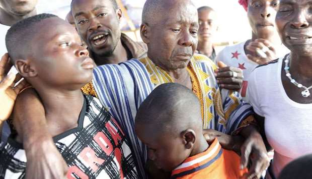 Exiled Ivorian children Hurbain Souomi (left) and Thierry Souomi are hugged by their grandfather Lah Justin on their return in their village in Goulaleu.