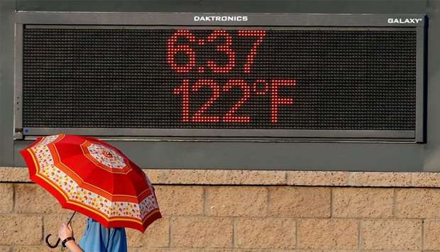 A pedestrian walks past a sign displaying the time and temperature in Arizona