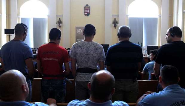 Defendants stand in the court room, ahead of the trial in which they are charged with causing the de