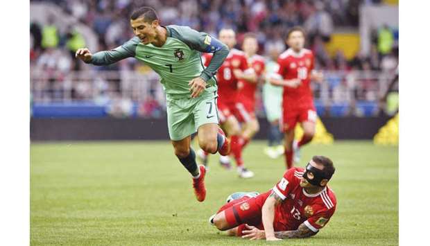 Portugalu2019s forward Cristiano Ronaldo (left) falls to the ground as Russiau2019s defender Fedor Kudryashov  looks on during the Confederations Cup group A match at the Spartak Stadium in Moscow yesterday. (AFP)