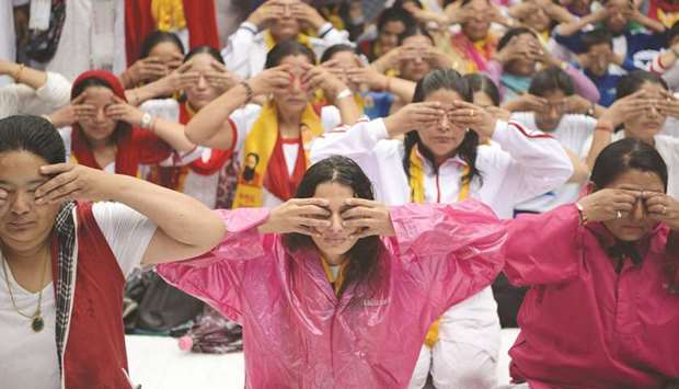 Yoga practitioners gather in the rain to take part in a yoga session on International Yoga Day in Kathmandu yesterday.