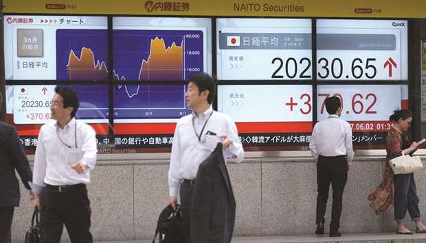 Pedestrians walk past a stock quotation board flashing the key Nikkei index in front of a securities firm in Tokyo. Japanese stocks rallied to a near two-year high yesterday.
