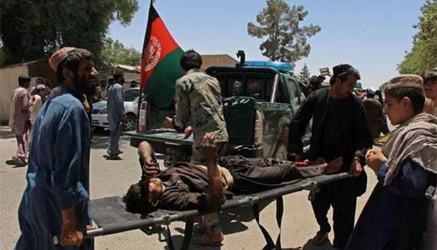 Afghan men carry a victim of a powerful car bomb in Lashkar Gah, the capital of Helmand province, on Thursday.