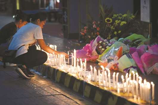 Employees light candles during a memorial for those killed in a casino fire caused by a gunman at Resorts World in Pasay City, Metro Manila, yesterday.
