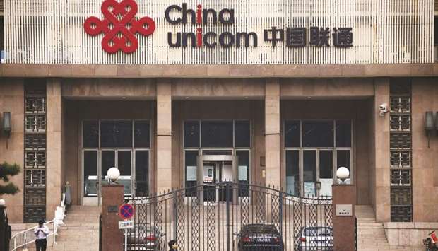 People walk past the China Unicom office building in Beijing. The company plans to raise around 70bn yuan ($10.25bn) through the Shanghai unit, sources said yesterday.