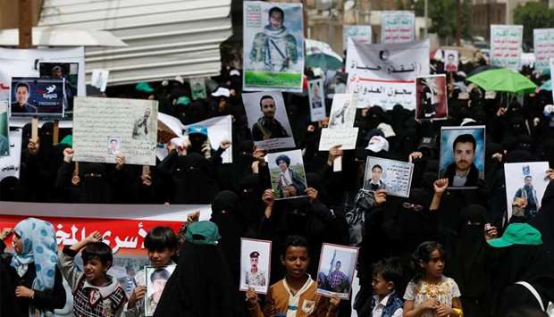 Women and children hold up posters of relatives who they said are taken as prisoners of war by government forces in Yemen
