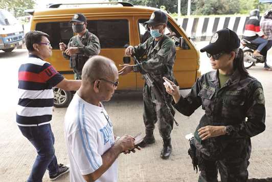 Members of the Philippine Army check the identity of bus passengers at a check point outside Iligan, as government forces continue their assault against insurgents from the Maute group, yesterday.