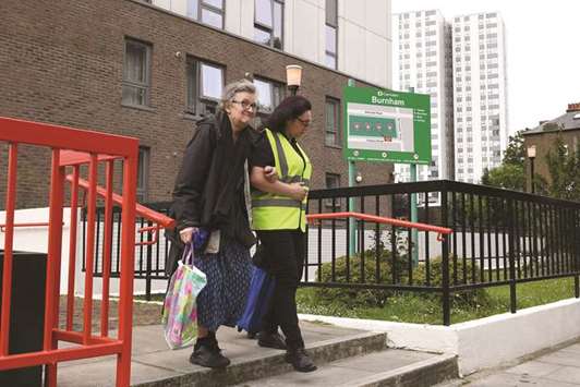 A resident is helped by a council official as she leaves Burnham Tower residential block.