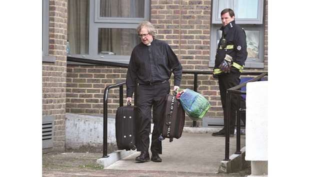 A vicar helps residents evacuate the Dorney Tower residential block in north London.