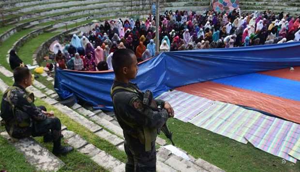 Members of the police special action force stand guard as Muslims, who fled the conflict in Marawi, pray during Eid al-Fitr