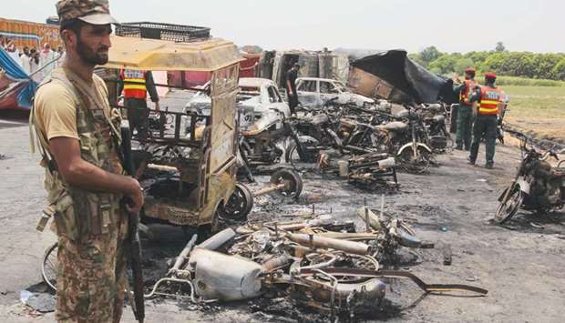 Pakistani soldiers stand guard beside burnt out vehicles at the scene where an oil tanker caught fire following an accident on a highway near the town of Ahmedpur East, some 670km from Islamabad yesterday.