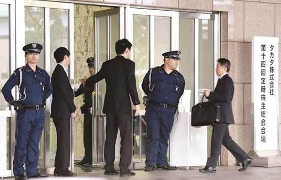 Employees lead a shareholder (right) to the venue of the annual shareholdersu2019 meeting of Japanu2019s crisis-hit Takata in Tokyo yesterday, a day after the company filed for bankruptcy protection. The company is facing lawsuits and huge costs over a defect blamed for at least 16 deaths and scores of injuries, with the scandal affecting almost every major global automaker.