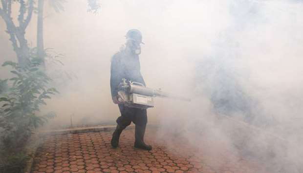 A worker fumigates a residential area to prevent the spreading of dengue fever by mosquitoes.