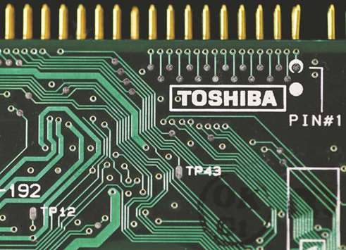 A logo of Toshiba Corp is seen on a printed circuit board in Tokyo. The company has pushed back its timeline to clinch a sale of its prized flash memory chip unit, saying the $18bn deal was being held up due to differences of opinion within the consortium chosen as preferred bidder.