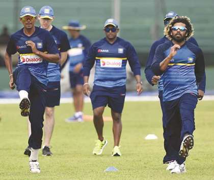 Sri Lankan cricketer Lasith Malinga (R) warms up with teammate Dushmantha Chameera (L) during a practice session at Galle International Cricket Stadium in Galle. (AFP)