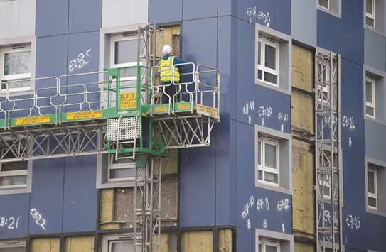 A worker removes cladding from a residential tower block in Cranford in west London yesterday.