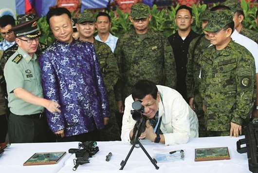 President Rodrigo Duterte checks the scope of a 7.62mm sniper rifle during the turnover ceremony of Chinau2019s urgent military assistance given u201cgratisu201d to the Philippines, in Clark Air Base, near Angeles City, yesterday. Also in picture: Wang Xianyun (left) military and  defence attache of China, Zhao Jianhua (second left), ambassador of Peopleu2019s Republic of China to the Philippines, and Philippine Armed Forces Chief of Staff Lt Gen Eduardo Ano (right).