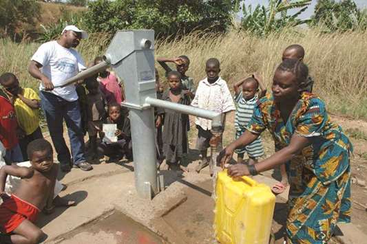 Women and children gather around a communal water pump in Lulimba, Democratic Republic of The Congo.