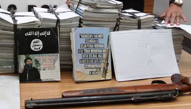 Indonesian police show scores of notebooks inscribed with Islamic State propaganda seized during a raid on the home of suspected militant during a press conference at police headquarters in Jakarta, Indonesia.