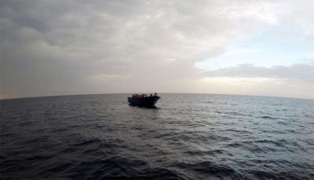 Migrants on a wooden boat wait to be rescued