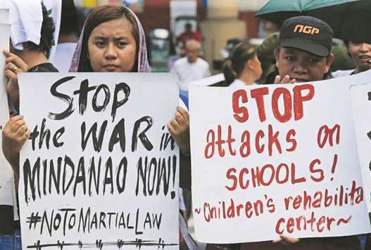 Activists hold placards calling for peace in war-torn Marawi as they join other protesters on President Rodrigo Duterteu2019s first year in office during a rally outside the presidential palace in Metro Manila, yesterday.