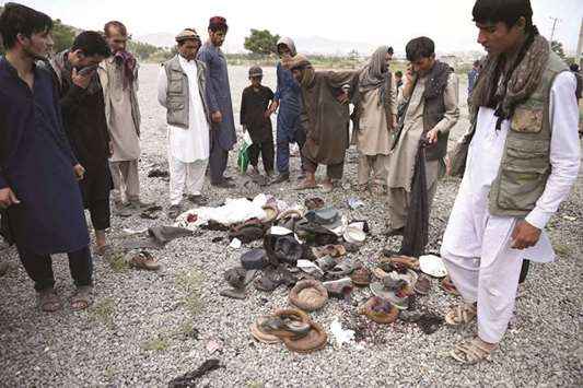 Afghan men stand over the belongings of blast victims at the site of a series of explosions that targeted a funeral of a politicianu2019s son, who was killed during an anti-government protest a day earlier, at Badam Bagh in Kabul yesterday.