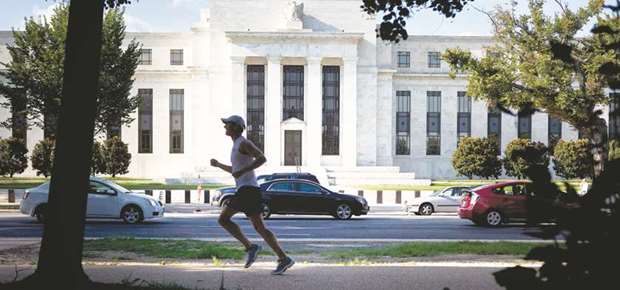 A runner passes the Federal Reserve building in Washington, DC. The market is pricing in an 83% chance the central bank raises its benchmark rate by a quarter-point, based on the current effective funds rate and the forward overnight index swap rate.