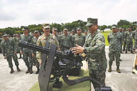 Philippine Marines Commandant Emmanuel Salamat (front right) tries a new M134D Gatling-style machine gun while Colonel Ernest Lee (centre left) from the US military looks on during a handover ceremony of weapons from the US military, at Marine headquarters in Manila yesterday.
