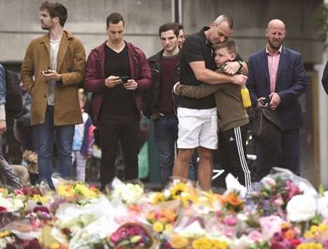 A man embraces a boy as they look at flowers left on the south side of London Bridge near Borough Market after an attack left seven people dead and dozens of injured in London yesterday.