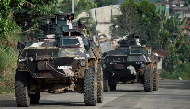 Armoured personnel carriers drive down a village road in Marawi