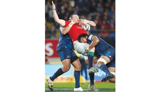 British and Irish Lions captain Ken Owens (C) is tackled by Bluesu2019 Alex Hodgman (L) and Steven Luatua (R) during their match at Eden Park in Auckland yesterday.
