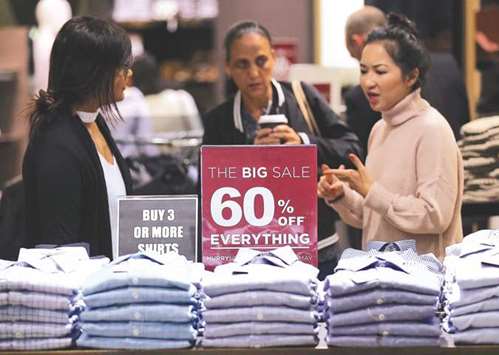 A shop assistant talks to customers in front of a sales sign on display at a retail store in Sydney. The Australian economy grew 0.3% in the three months to March for an annual rate of 1.7%, the Australian Bureau of Statistics said yesterday.