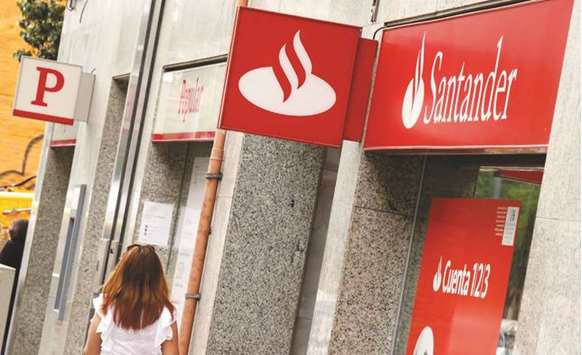 A woman walks past a Banco Popular and Santander banks branches in Barcelona. Santander will raise about u20ac7bn ($7.9bn) in a rights offer to bolster Popularu2019s balance sheet, acquiring the lender for u20ac1, according to a regulatory filing yesterday.