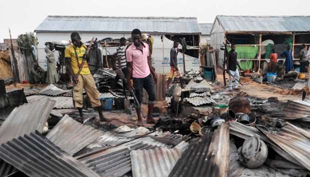 Armed members of a local defence group inspect the damages of a suicide blast in Maiduguri. AFP
