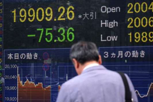 A man walks in front of a share price board in Tokyo. Japanu2019s Nikkei ended 0.4% lower at 19,909.26 yesterday, hit by profit-taking and news that the Japanese economy grew at a slower rate than first thought in January-March.