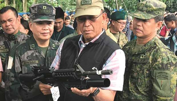 Philippines Defense Secretary Delfin Lorenzana inspects a firearm seized from militants.