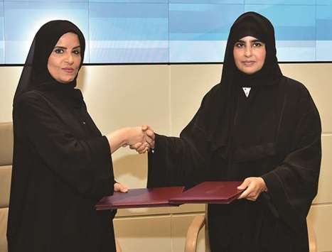 Amal bint Abdul-Latif al-Mannai shakes hands with Prof Mariam al-Maadeed after signing the contract.