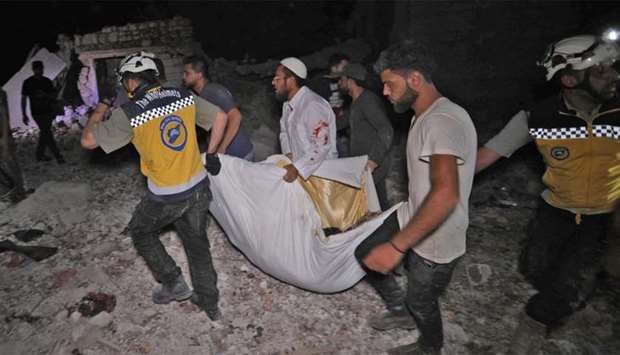 Syrian rescuers carry an injured person in Zardana following air strikes