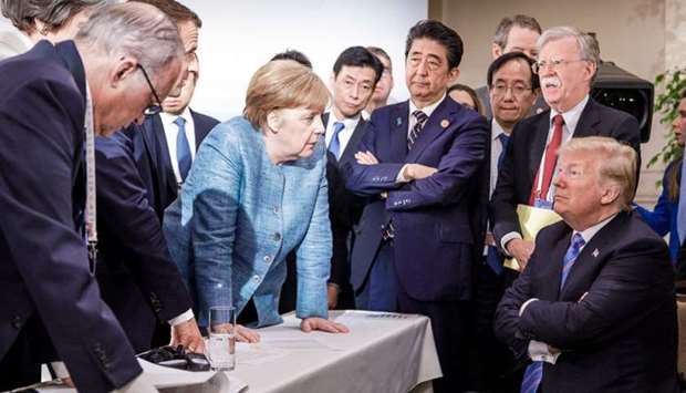 US President Donald Trump (R) talking with German Chancellor Angela Merkel (C) and surrounded by other G7 leaders during a meeting of the G7 Summit in La Malbaie, Quebec, Canada.