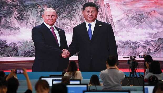 A large video screen shows Chinese President Xi Jinping shaking hands with Russia's President Vladimir Putin