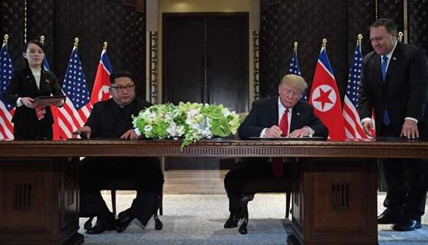 US President Donald Trump (2nd R) and North Korea's leader Kim Jong Un (2nd L) sign documents as US Secretary of State Mike Pompeo (R) and the North Korean leader's sister Kim Yo Jong (L) look on at a signing ceremony during their historic US-North Korea summit, at the Capella Hotel on Sentosa island in Singapore