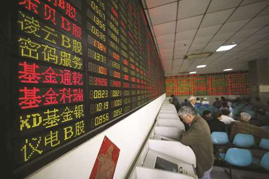 Investors look at computer screens showing stock information at a brokerage house in Shanghai. The Composite closed up 0.9% to 3,079.80 points yesterday.